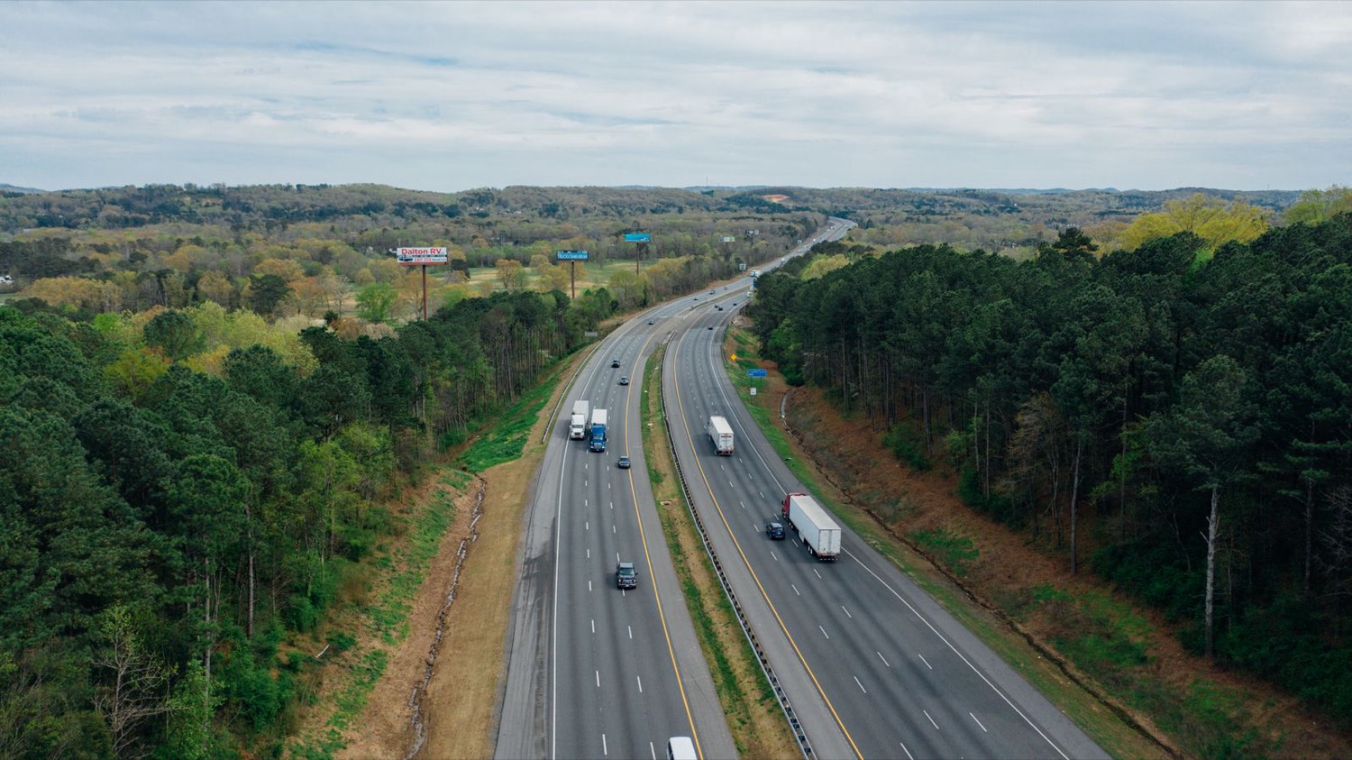 Büyük yol iyileştirmesi: yeşil kırsaldan geçen bölünmüş bir otoyolun havadan görünümü